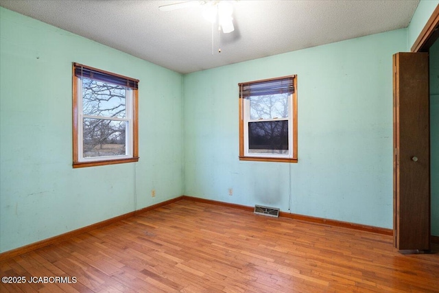 unfurnished room with ceiling fan, a healthy amount of sunlight, light hardwood / wood-style floors, and a textured ceiling