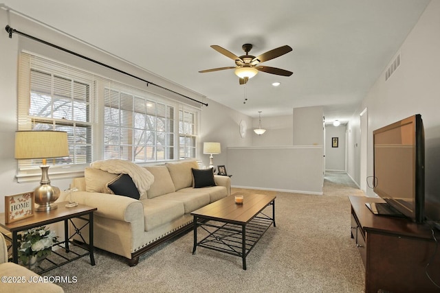 carpeted living room with visible vents, baseboards, and a ceiling fan