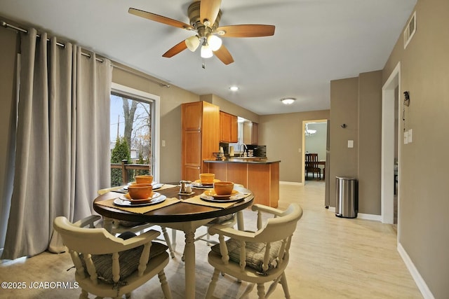 dining room featuring visible vents, baseboards, light wood-type flooring, and a ceiling fan