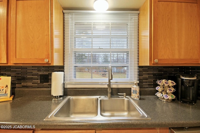 kitchen with tasteful backsplash, dark countertops, and a sink