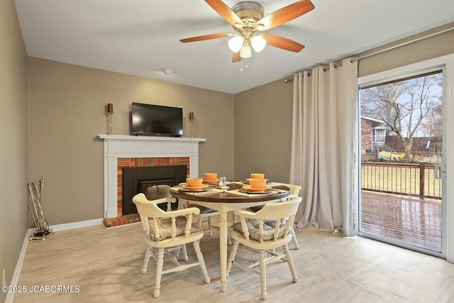 dining area with a ceiling fan, a fireplace, and baseboards