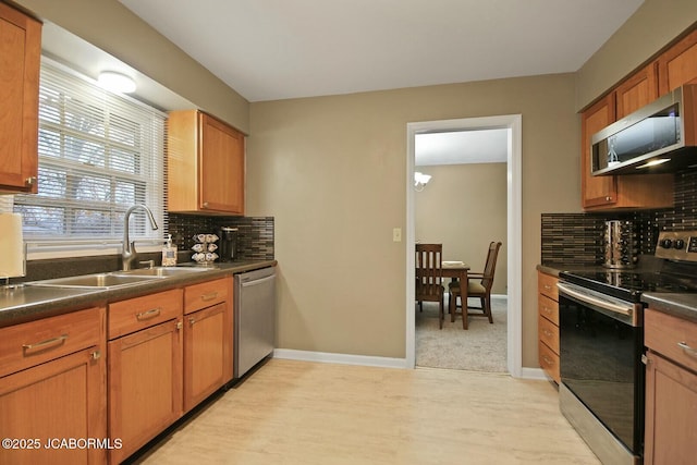 kitchen with a sink, stainless steel appliances, dark countertops, and backsplash