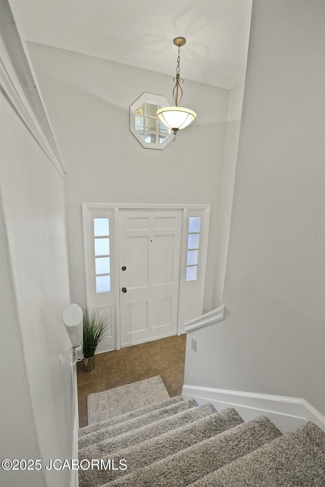 tiled foyer entrance featuring stairway and baseboards