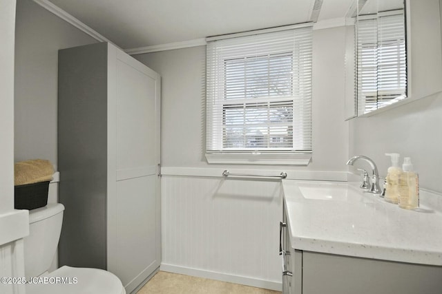 bathroom featuring vanity, toilet, a wainscoted wall, and ornamental molding