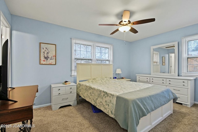 bedroom with a ceiling fan, baseboards, and light carpet