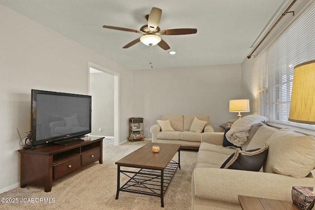 living area with light carpet, baseboards, and ceiling fan