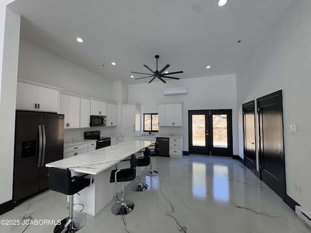 100 Blue Heron Hill Ln Unit 103, Lake Ozark, MO 65049 - kitchen featuring black appliances, a high ceiling, a breakfast bar, white cabinetry, and a spacious island