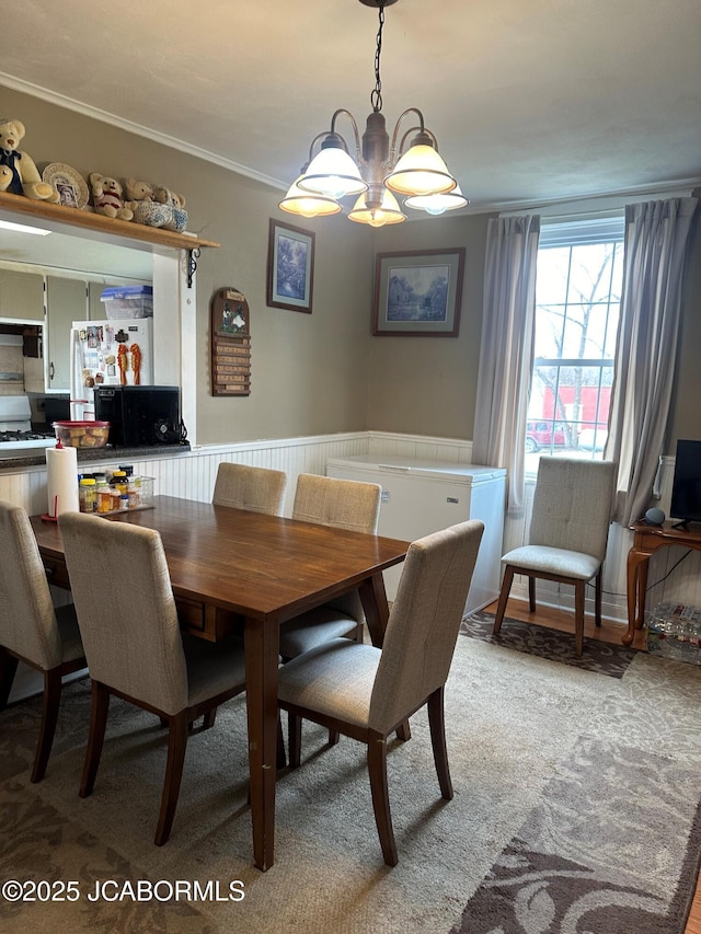 dining room with crown molding, light colored carpet, and an inviting chandelier