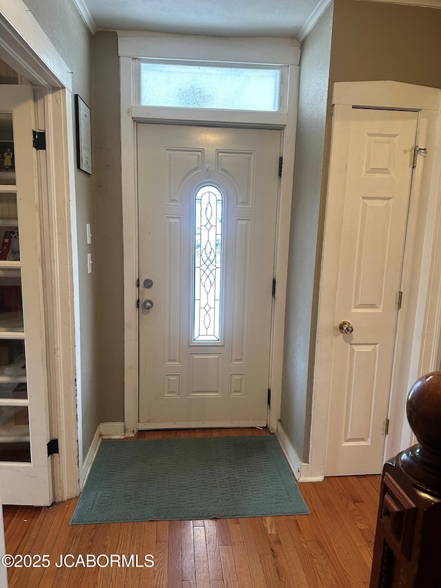 foyer entrance with crown molding and light wood-type flooring