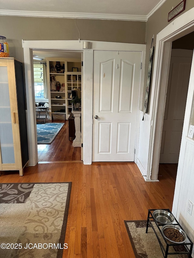 corridor with ornamental molding and hardwood / wood-style floors