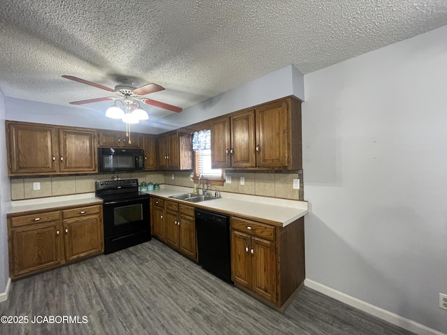 kitchen featuring dark wood-style floors, light countertops, backsplash, a sink, and black appliances