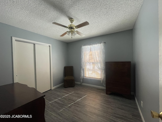 unfurnished bedroom with dark wood-type flooring, a textured ceiling, ceiling fan, and a closet