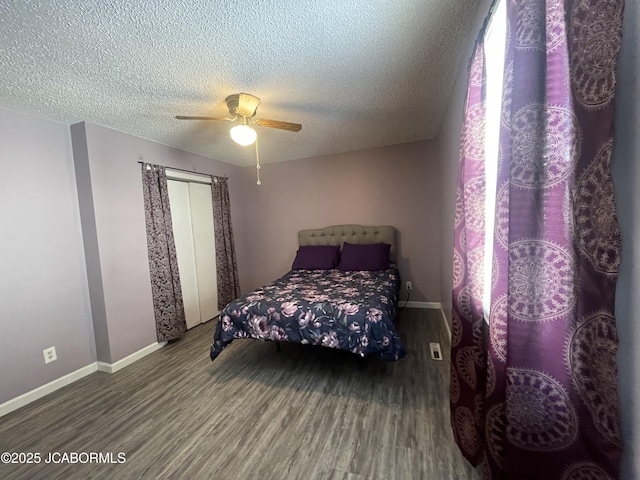 bedroom featuring a ceiling fan, a textured ceiling, baseboards, and wood finished floors