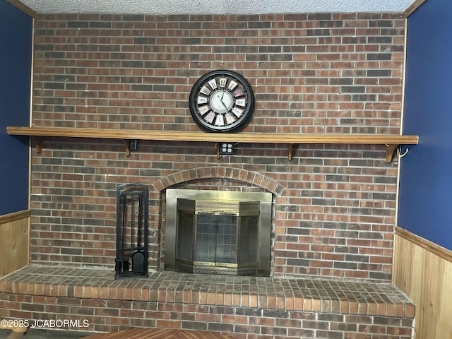 room details featuring a fireplace, a textured ceiling, and wood walls