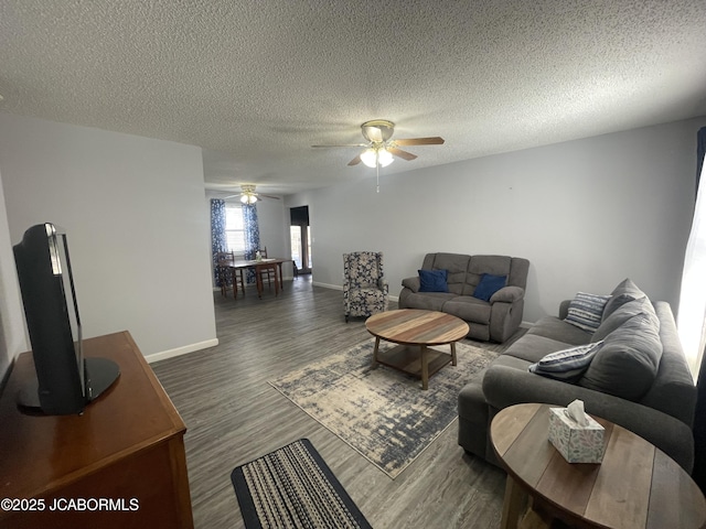 living room featuring a textured ceiling, ceiling fan, wood finished floors, and baseboards