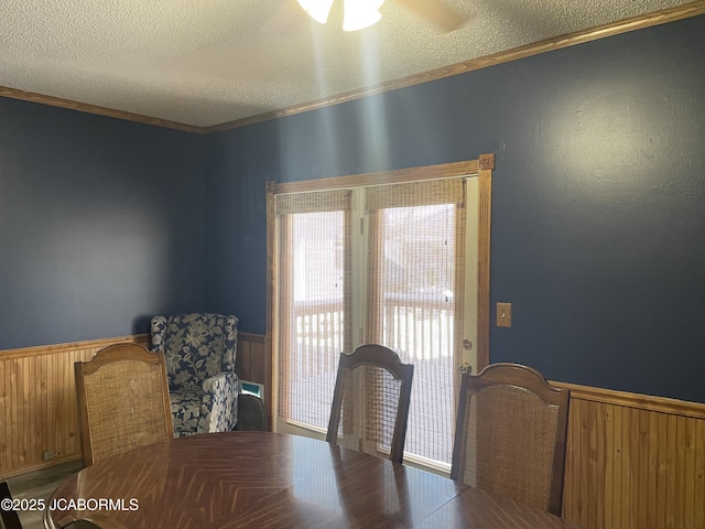 dining space featuring ceiling fan, crown molding, wood walls, and a textured ceiling