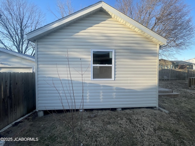 view of home's exterior featuring fence and an outbuilding