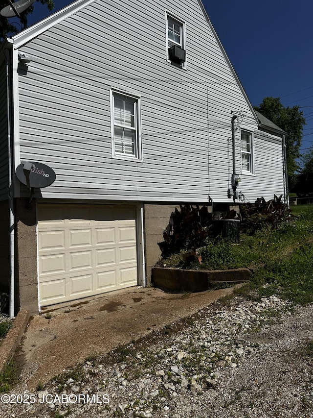 618 E Jefferson St, Linn, MO 65051 - view of property exterior with an attached garage, cooling unit, and dirt driveway