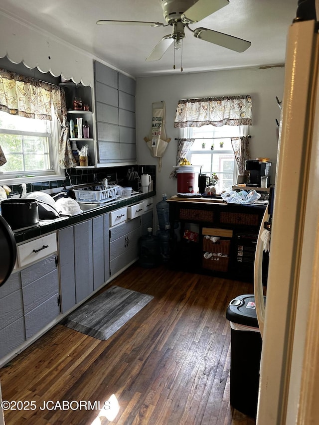 618 E Jefferson St, Linn, MO 65051 - kitchen featuring dark wood finished floors, gray cabinetry, a ceiling fan, tile countertops, and backsplash