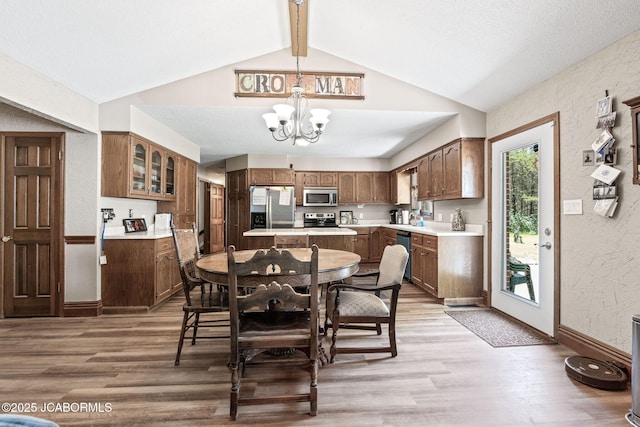 dining space featuring light wood finished floors, a chandelier, baseboards, and vaulted ceiling