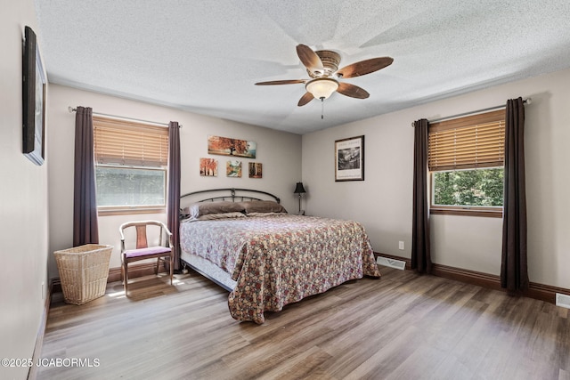 bedroom featuring a textured ceiling, baseboards, and wood finished floors