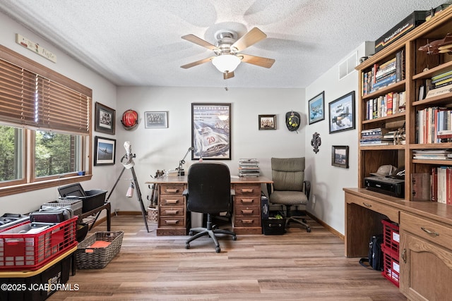office space featuring light wood finished floors, visible vents, a textured ceiling, and a ceiling fan