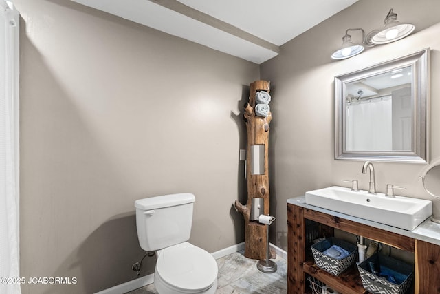 bathroom featuring vanity, toilet, and baseboards