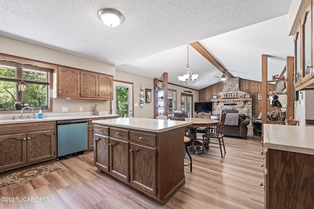kitchen featuring a sink, light wood-style floors, light countertops, dishwasher, and vaulted ceiling with beams