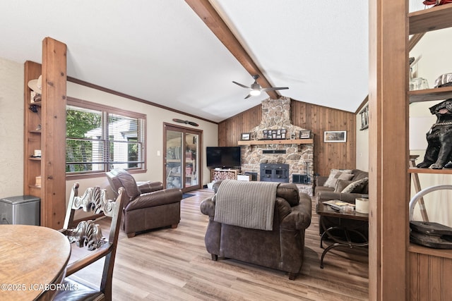 living room featuring wooden walls, lofted ceiling with beams, light wood-style flooring, a fireplace, and ceiling fan