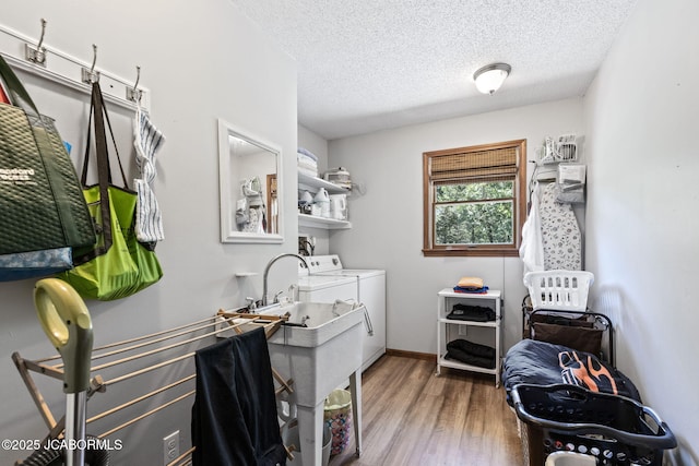 clothes washing area featuring laundry area, wood finished floors, separate washer and dryer, and a textured ceiling
