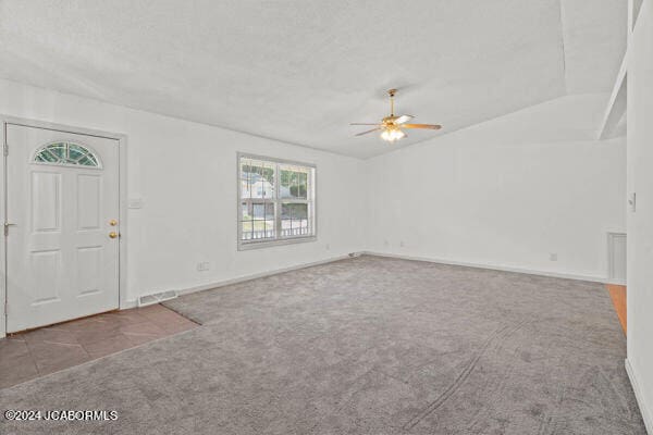 carpeted foyer entrance with ceiling fan and vaulted ceiling