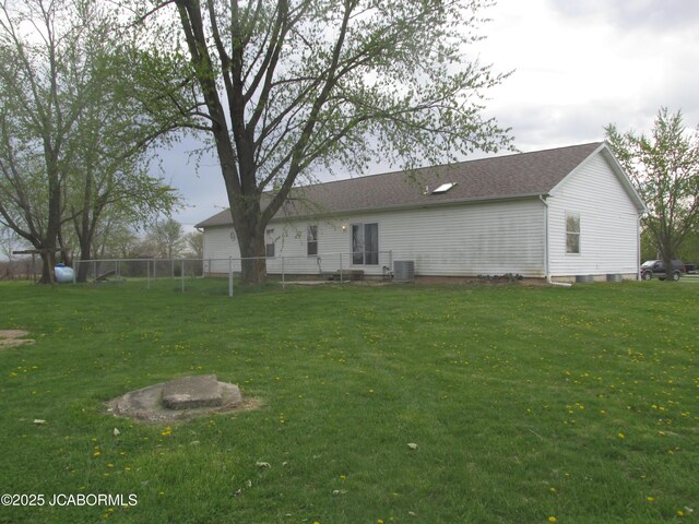 back of property with cooling unit, fence, and a lawn