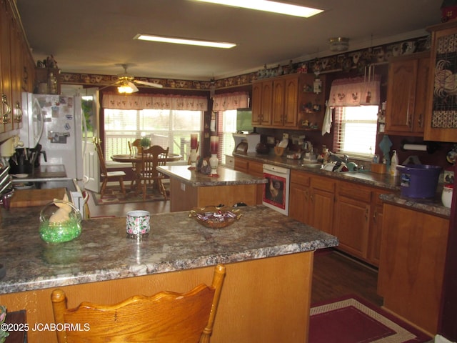 kitchen featuring a center island, brown cabinetry, a sink, and a ceiling fan