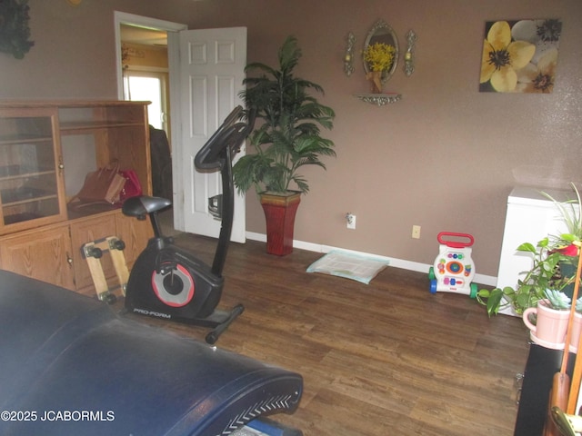 workout area with baseboards and wood finished floors