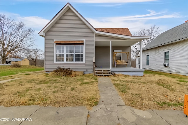 bungalow with a porch, a front yard, and cooling unit