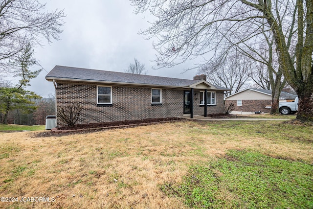 ranch-style home featuring cooling unit and a front lawn