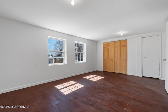 unfurnished bedroom featuring baseboards and dark wood finished floors