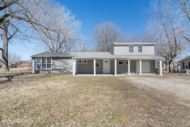 traditional-style house with a porch, an attached garage, driveway, and a front yard