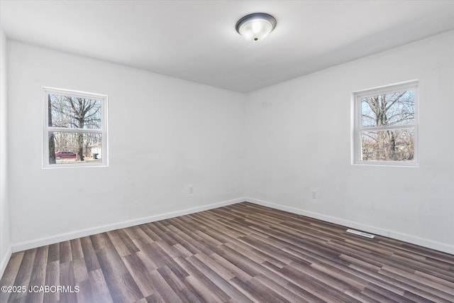 empty room with dark wood-type flooring and baseboards