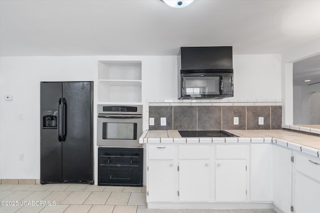 kitchen with white cabinetry, black appliances, tile counters, and decorative backsplash