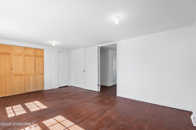 unfurnished bedroom featuring baseboards and dark wood-type flooring