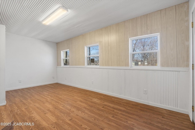 empty room with a healthy amount of sunlight, baseboards, and wood finished floors