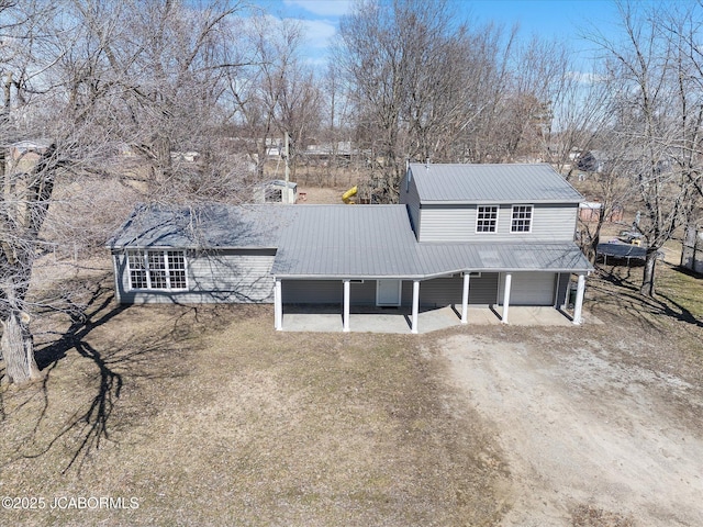 rear view of house with driveway and metal roof