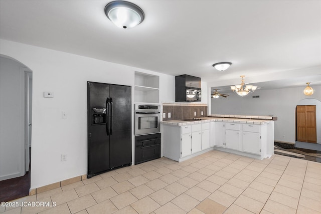 kitchen featuring light tile patterned floors, a peninsula, arched walkways, black appliances, and white cabinetry