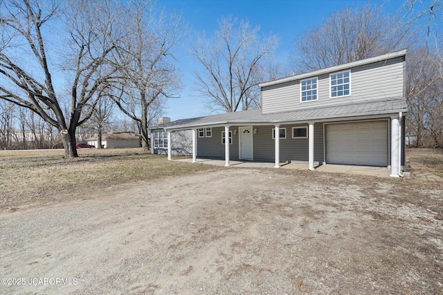 traditional-style house featuring covered porch, driveway, and an attached garage