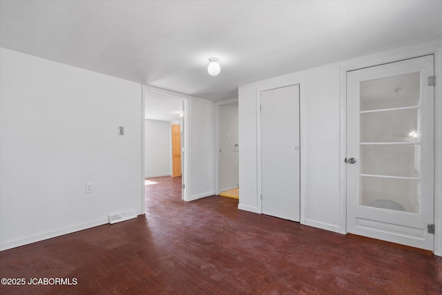 unfurnished bedroom featuring wood finished floors, baseboards, and visible vents