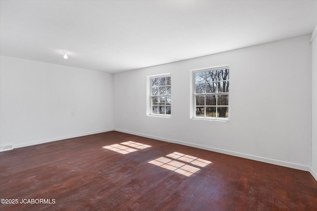 spare room with baseboards and wood finished floors