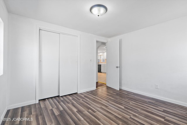 unfurnished bedroom featuring a closet, arched walkways, baseboards, and dark wood-style flooring