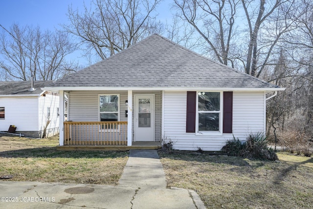 bungalow-style home featuring covered porch, roof with shingles, and a front yard