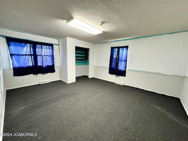 carpeted empty room with a textured ceiling